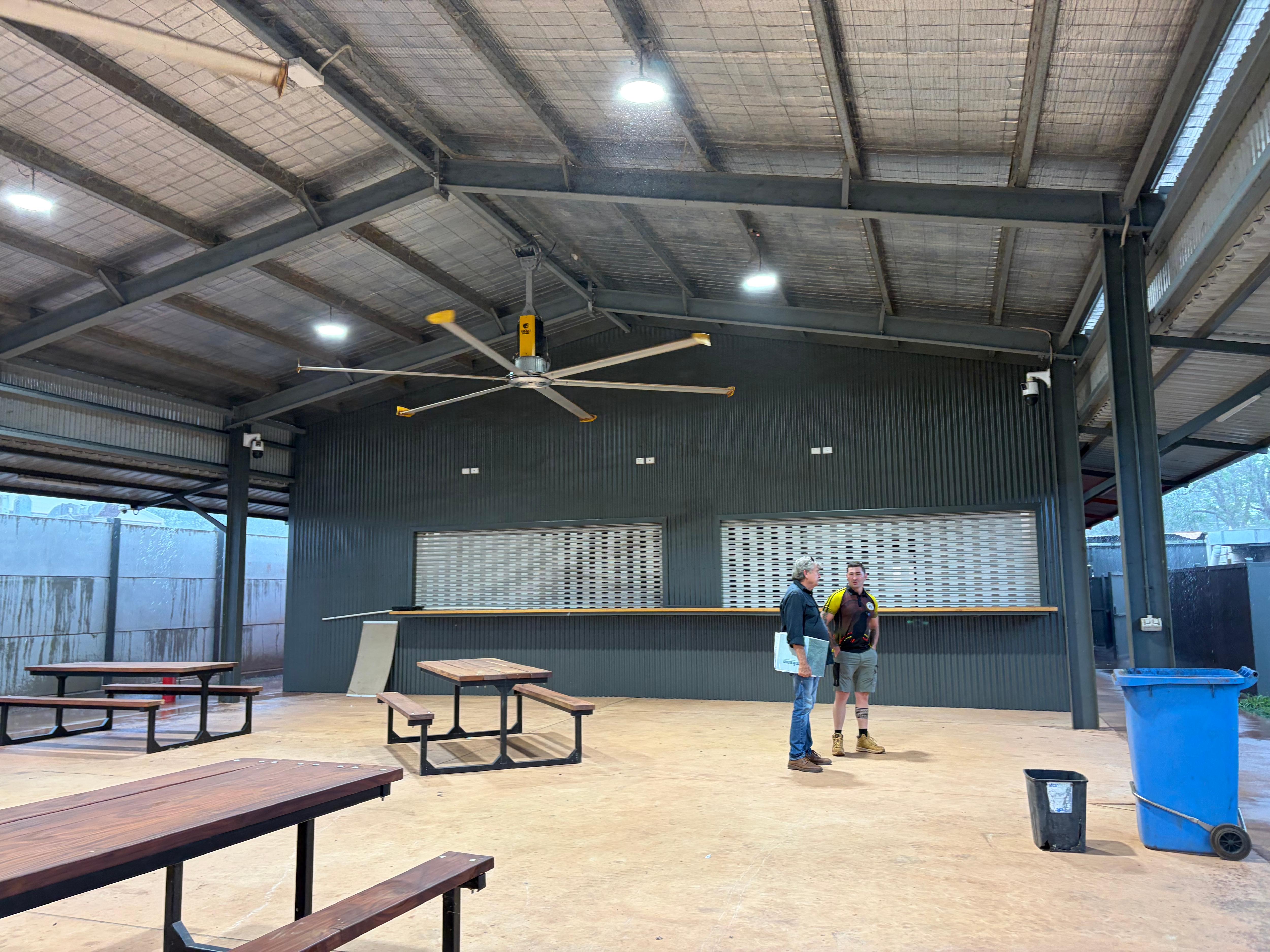 Bill Ivory and Jake Clark standing in an undercover social area with large ceiling fan overhead.