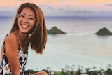 Vivian Wong sits on a cliff edge overlooking a view
