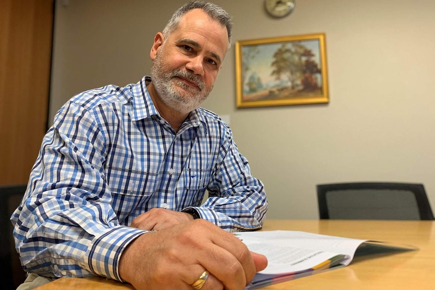 Greg Chemello sits at a desk with a report.