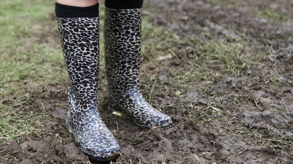 Leopard print gumboots standing in the mud.