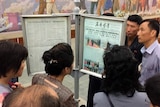 Korean residents look at a news paper sign.