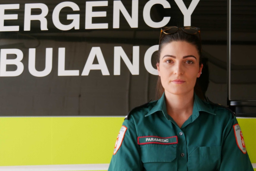 Paramedic Amy McCaffrey stands in front of an ambulance.