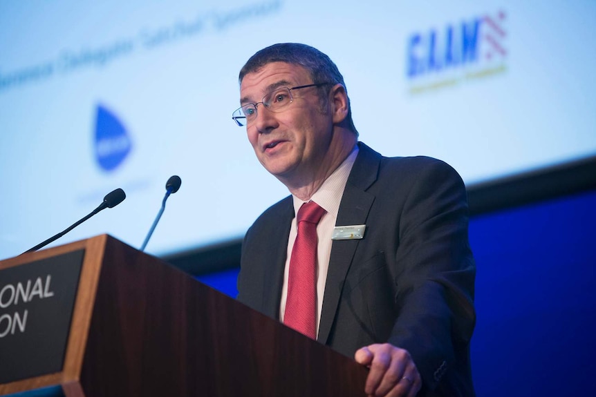 Dr Richard Thornton stands at a lectern while addressing a conference.