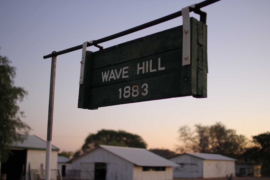 A sign hanging off a metal bar that reads "Wave Hill 1883".