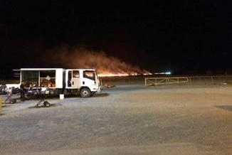 A long line of fire burns in the distance at night.