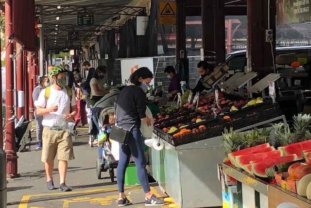 People wearing masks shopping for fruit and vegetables.