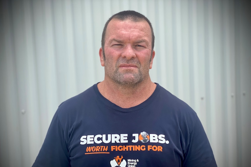 A man with close-cropped hair, stubble and a union T-shirt.