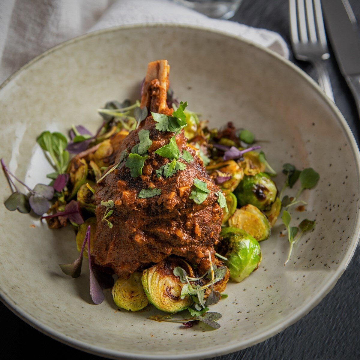 A dish of meat with vegetables including brussel sprouts, presented very nicely on a plate.