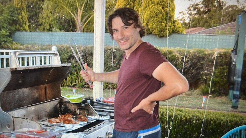 A man in a brown shirt cooking a bbq in a suburban backyard