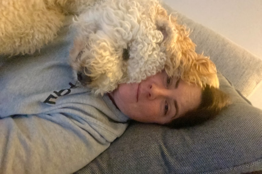 Image of a woman lying on a couch with a sleeping puppy