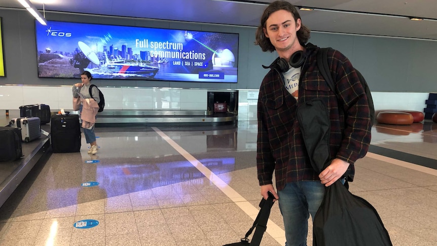 A young man gets his bag from a baggage carousel.