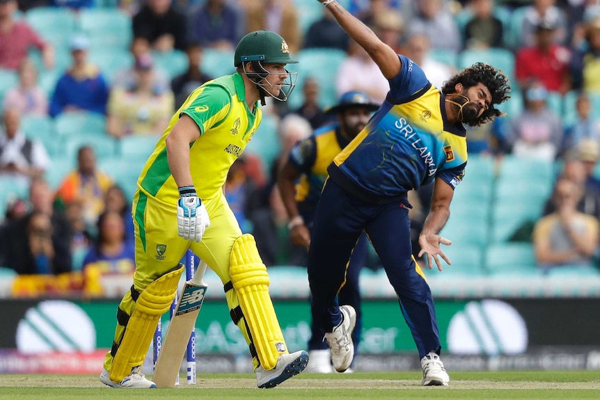 Lasith Malinga grimaces as he releases the ball. Next to him, non-striker Aaron Finch looks down the pitch and prepares to run.