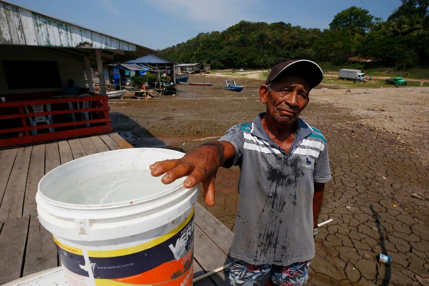 67 year-old man shows the water he obtained from a well dug in the dry bed of Puraquequara Lake amid a severe drought