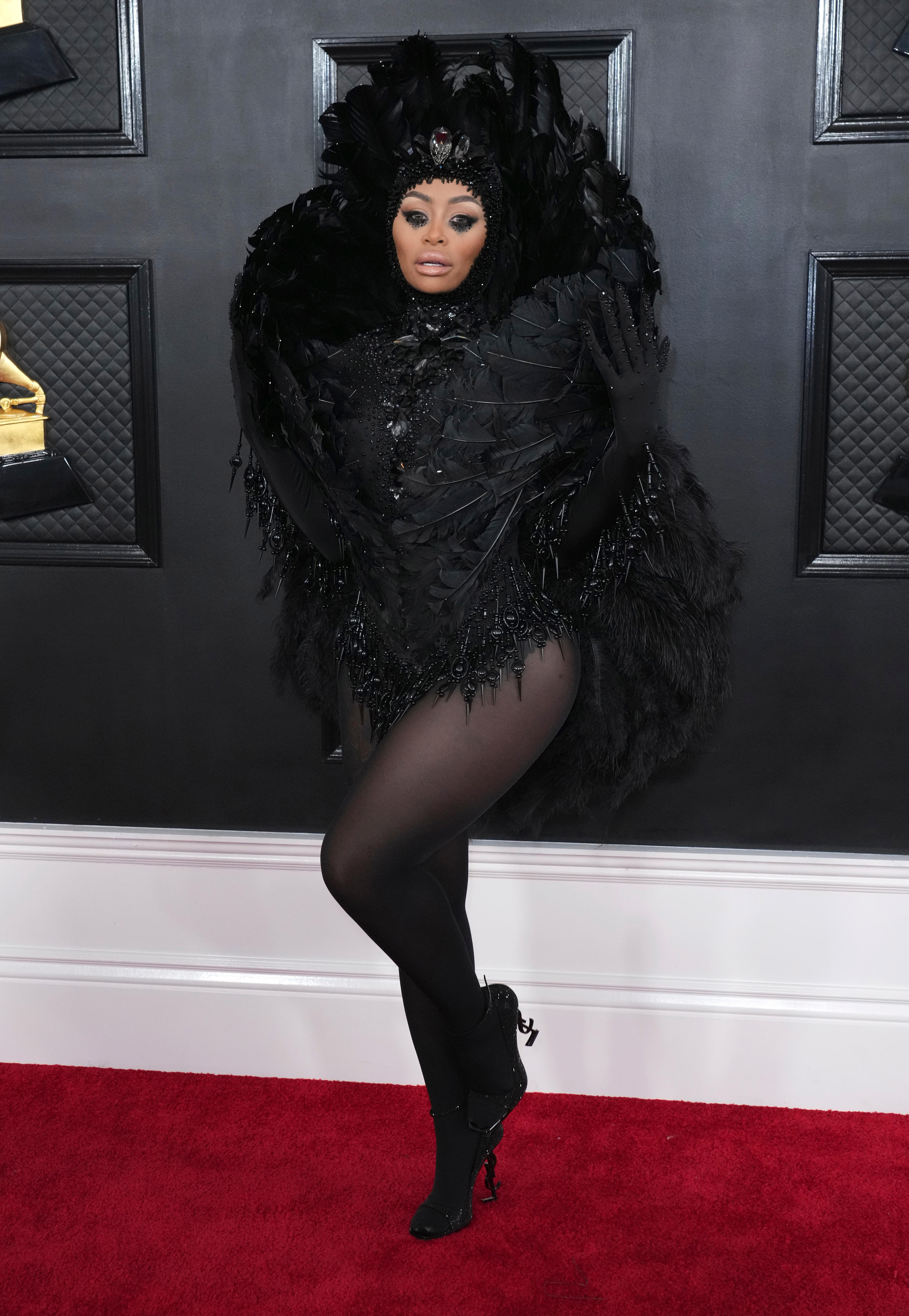 Blac Chyna wearing a black feathered leotard with a matching feathered head dress. 