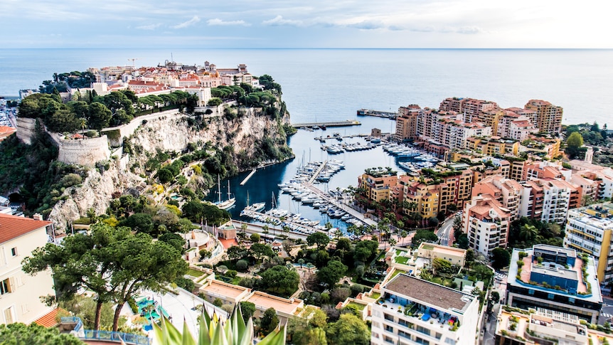 A view of Monaco: Apartment buildings and old buildings surrounding a large harbour filled with boats