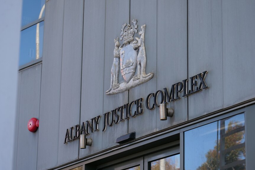 A metal sign saying "Albany Justice Complex" with the West Australia Coat of Arms above.