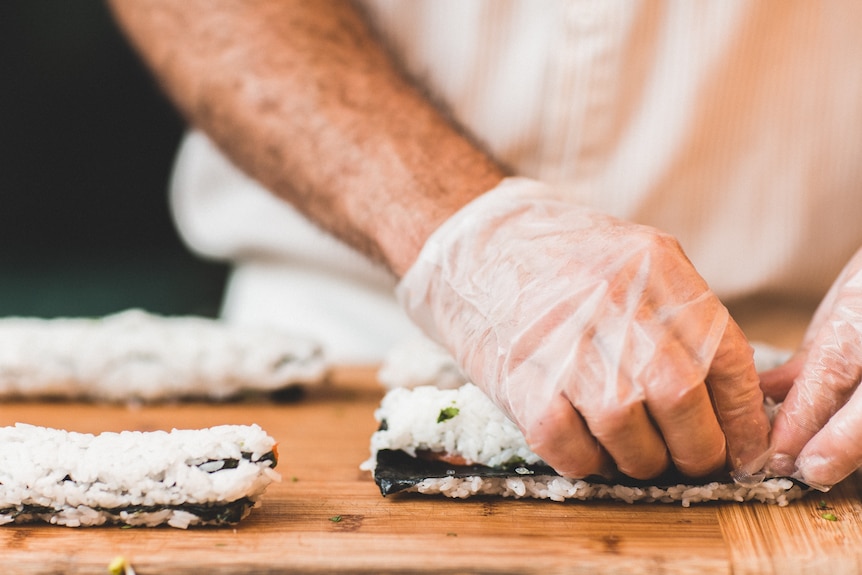 Close up of man's hands making sushi using rice