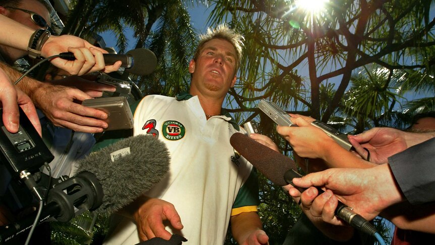 Shane Warne surrounded by journalists and cameras