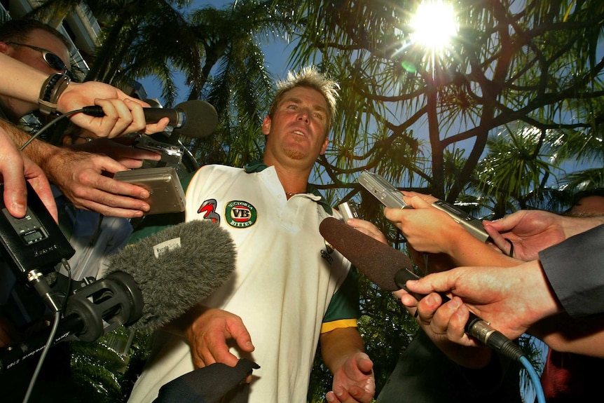 Shane Warne surrounded by journalists and cameras