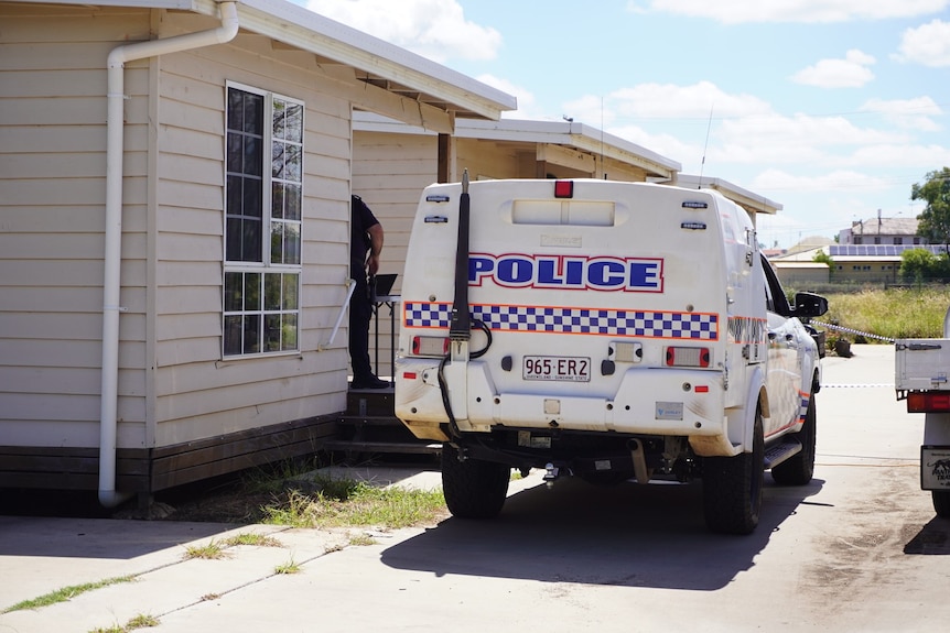 A police vehicle parked outside a small house.