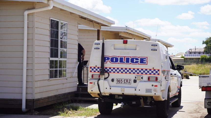 A police vehicle parked outside a small house.