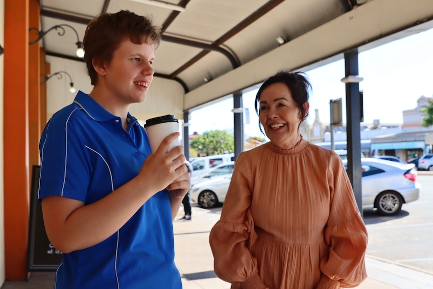 young disabled woman hands a coffee cup to a customer on the main street in Kalgoorlie