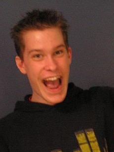 A young teen poses for a photo with his mouth open in a wide smile-like expression