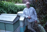 A man poses with bee hives