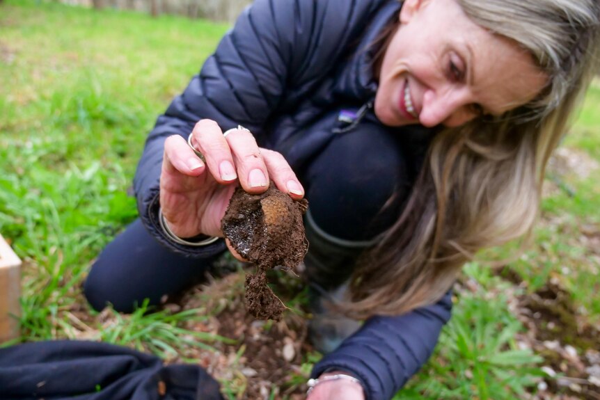 A woman holds a truffle she dug from the ground.