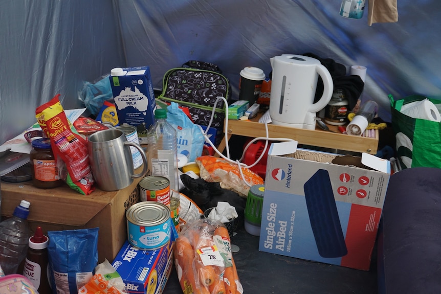A collection of household food items and appliances sitting inside a tent.