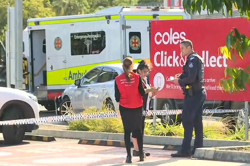 A police officer talks to people at a Nambour carpark where the accident happened.