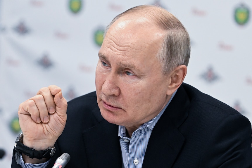 Vladimir Putin gestures with his thumb and finger 
