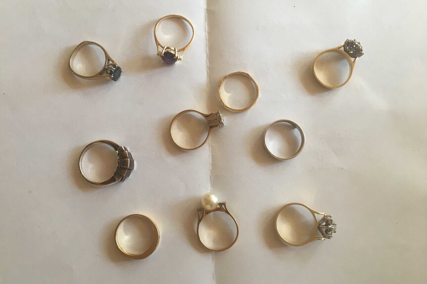 10 rings sit on a piece of paper, some with bright stones and others more plain bands.