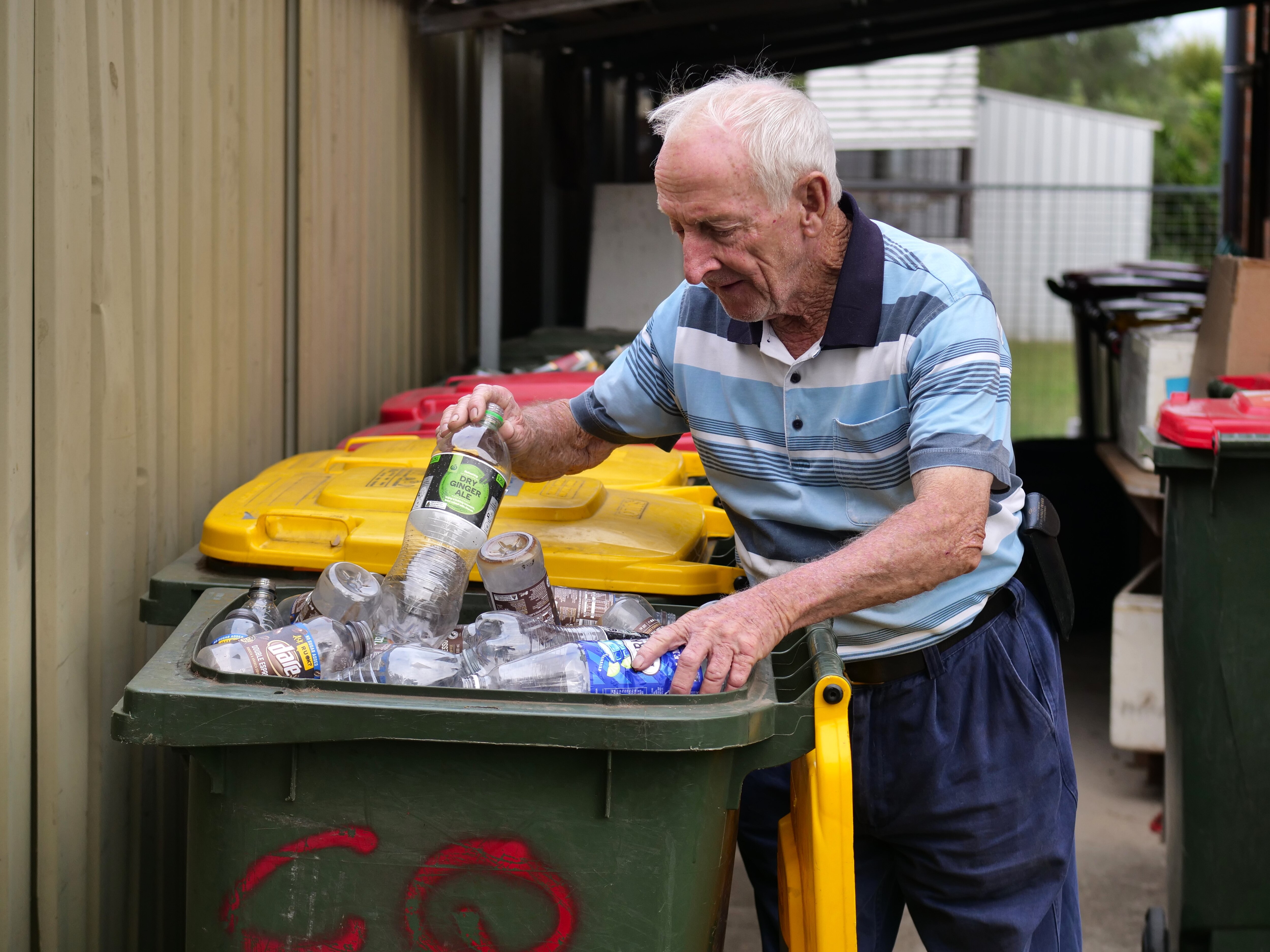A man with white hair sorts through containers in a bin