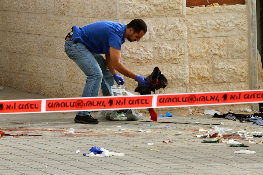 An Israeli policeman searches the bus site
