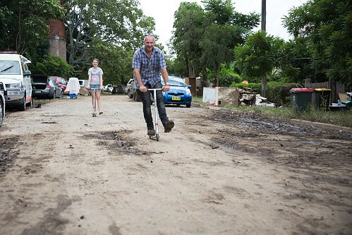A man rides his scooter down a dirty street in Murwillumbah