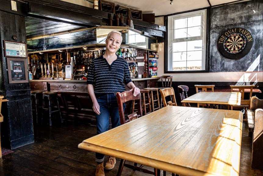 A blonde woman smiling while standing in the dining room of a British pub