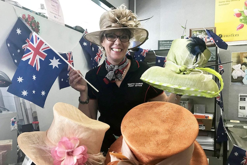 Melissa Harwood shows off her selection of formal hats and Australian flags for the royal visit of Prince Charles to Cairns.