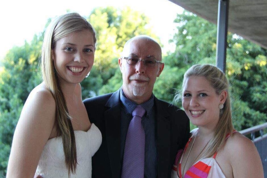 Two smiling girls with their dad Anthony Vanderwey in a family portrait.