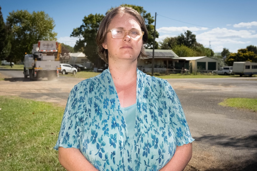 A woman stands next to a dusty intersection