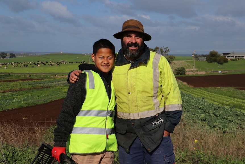 a student and a farmer stand next to each other in  field.