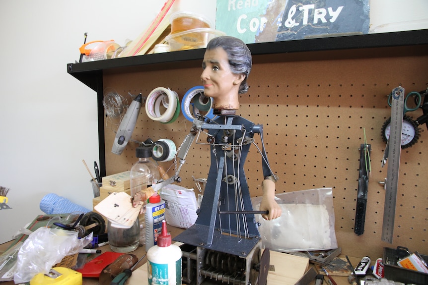 An automaton and head of a machine stand on a workshop bench inside Jason Coultis' garage.