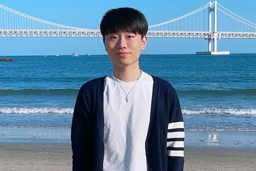 a young man standing in front of a bridge looking ahead