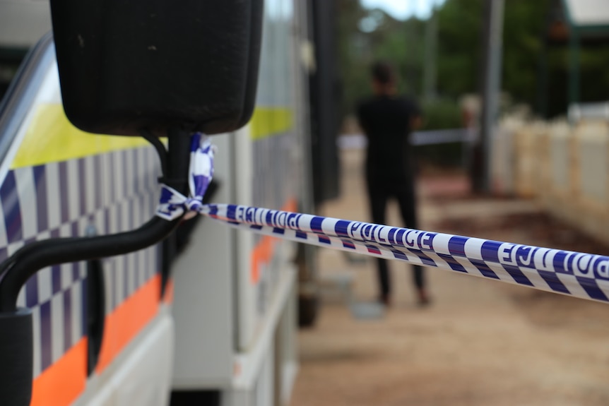 Close up on police tape with police van blurred in the background 