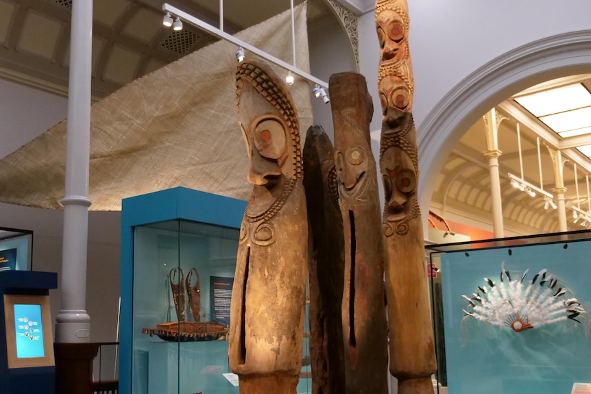A trio of massive carved PNG sculptures standing in the middle of the museum
