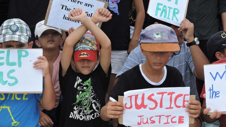 Refugee children hold up signs protesting their resettlement on Nauru