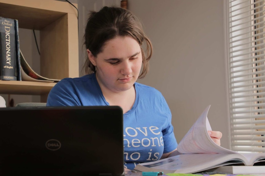 Maria Scharnke studies at a desk with a laptop and textbook.