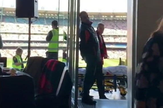 Two men stand near an ambulance stretcher outside a dining room at the MCG.