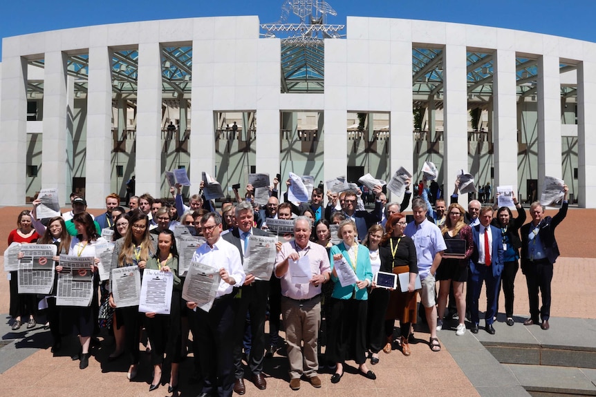 Journalists congregating outside Parliament House, holding up blacked out newspaper frontpages.