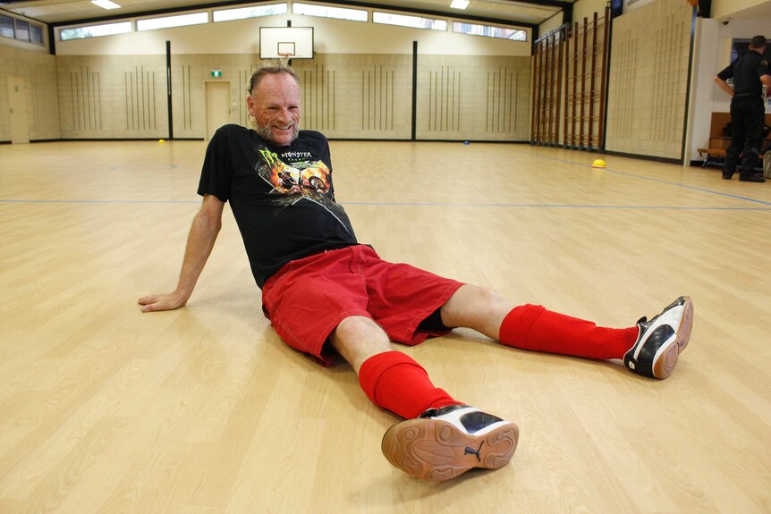Tim Dixon sitting on a futsal court in Launceston
